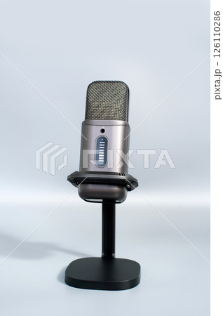 Modern gray microphone on stand against light background 126110286