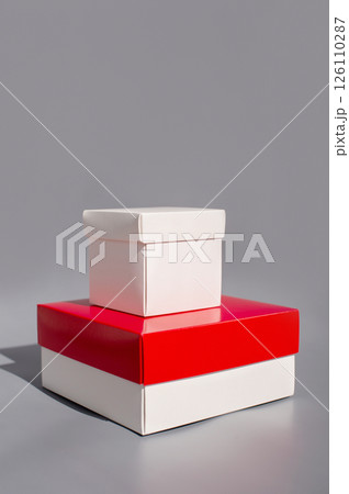 Stacked white and red gift boxes on gray background Stacked white and red gift boxes on gray background 126110287
