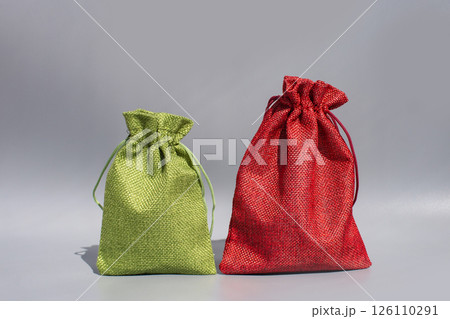 Green and red drawstring fabric pouches on gray background 126110291