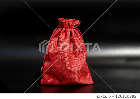 Vibrant red drawstring bag on black background showcasing texture and design 126110292