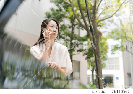 車の前でスマホで話す女性 126110567