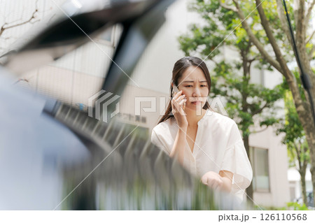 車の前でスマホで話す女性 126110568