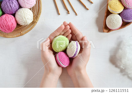 Making crochet amigurumi french macarons. Toy for babies or trinket. Threads, needles, hook, cotton yarn. Handmade gift. Income from hobby. DIY crafts concept. Making crochet amigurumi french macarons. Toy for babies or trinket. Threads, needles, hook, cotton yarn. Handmade gift. Income from hobby. DIY crafts concept. 126111551