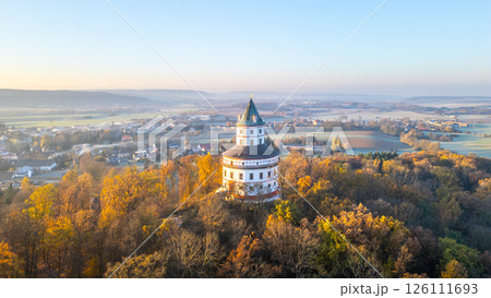 An elegant Baroque chateau with an elliptical floor plan stands majestically above the town of Sobotka, illuminated by the warm colors of an autumn sunrise over the Bohemian Paradise. An elegant Baroque chateau with an elliptical floor plan stands majestically above the town of Sobotka, illuminated by the warm colors of an autumn sunrise over the Bohemian Paradise. 126111693