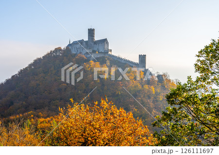 The medieval Bezdez Castle stands majestically atop a hill, surrounded by vibrant autumn foliage. This iconic Gothic structure showcases its historical significance in the Czech landscape. The medieval Bezdez Castle stands majestically atop a hill, surrounded by vibrant autumn foliage. This iconic Gothic structure showcases its historical significance in the Czech landscape. 126111697