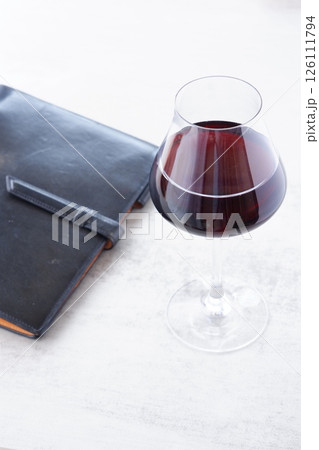赤ワインを飲みながら、黒い革のシステム手帳に日記をつけているイメージ 赤ワインを飲みながら、黒い革のシステム手帳に日記をつけているイメージ 126111794