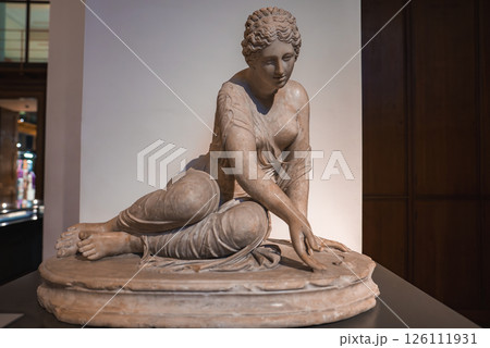 A marble statue of a seated woman with detailed drapery, one arm extended forward. The indoor setting includes display cases and soft lighting. 126111931