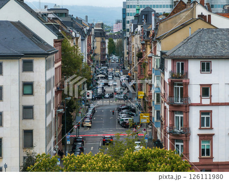 Urban scene in Frankfurt, Germany, featuring European style buildings, parked cars, trees, and distant modern office buildings blending old and new. 126111980