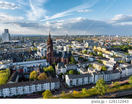 Aerial image of Frankfurt, Germany, highlighting St. Paul's Church, modern and traditional buildings, tree lined streets, and a partly cloudy sky. 126112043