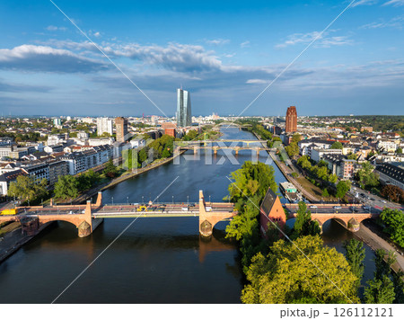 Aerial image of Frankfurt, Germany, featuring the Main River, European Central Bank, Alte Brucke, multiple bridges, and greenery under a clear blue sky. 126112121