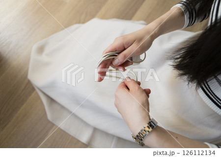 Woman unplugging and organizing phone charging cable 126112134