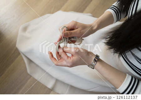 Woman unplugging and organizing phone charging cable 126112137