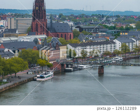 Aerial view of Frankfurt, Germany, featuring the Gothic Frankfurt Cathedral, the Main River with docked boats, Eiserner Steg, and mixed architecture. 126112289