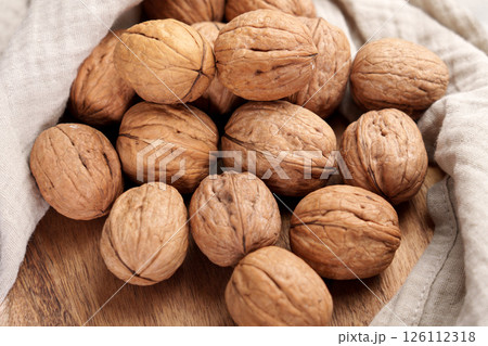 Walnuts on wooden table with crumpled linen cloth napkin. Walnuts on wooden table with crumpled linen cloth napkin. 126112318