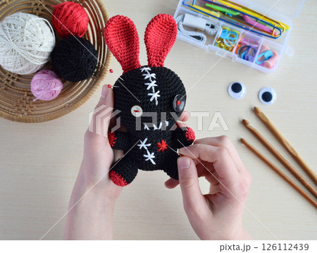 Making crochet voodoo rabbit. Toy for Halloween.  On the table threads, hook, cotton yarn. Handmade gift. Mystic, occult, horror DIY crafts concept. 126112439