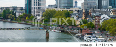 Scenic aerial view of Frankfurt, Germany, featuring the Eiserner Steg, the Main River with docked boats, modern skyscrapers, and historic architecture. Scenic aerial view of Frankfurt, Germany, featuring the Eiserner Steg, the Main River with docked boats, modern skyscrapers, and historic architecture. 126112470