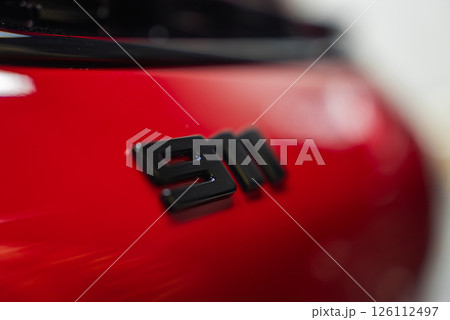 Close up view of the black 911 badge on the rear of a red 2025 Porsche 911 GT3 922. The glossy paint reflects light, with a blurred background. 126112497