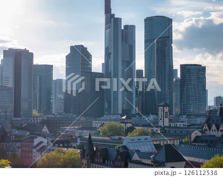 Modern skyscrapers, including Commerzbank Tower, rise above traditional European architecture in Frankfurt, Germany, under a partly cloudy sky. 126112538