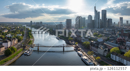 Aerial view of Frankfurt, Germany, featuring the Main River, Commerzbank Tower, Frankfurt Cathedral, Eiserner Steg, and greenery along the riverbanks. 126112557