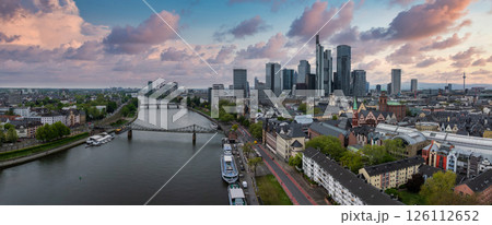 Aerial view of Frankfurt, Germany, featuring the Main River, Commerzbank Tower, Frankfurt Cathedral, Eiserner Steg bridge, and a vibrant sunset sky. Aerial view of Frankfurt, Germany, featuring the Main River, Commerzbank Tower, Frankfurt Cathedral, Eiserner Steg bridge, and a vibrant sunset sky. 126112652