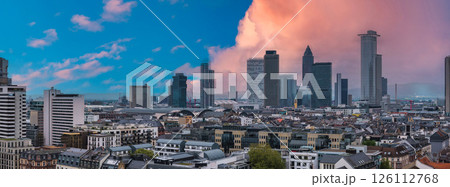 Aerial view of Frankfurt, Germany, featuring modern skyscrapers, traditional architecture, and the Hauptbahnhof under a vibrant sunset sky. 126112768