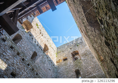 Looking up from the courtyard of Rabi Castle, the Donjon Tower rises against a clear blue sky. The stone walls are ancient, showing the castle's historical significance and unique architecture. Looking up from the courtyard of Rabi Castle, the Donjon Tower rises against a clear blue sky. The stone walls are ancient, showing the castle's historical significance and unique architecture. 126113296