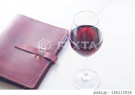 赤ワインを飲みながら、ワインレッドの革のシステム手帳に日記をつけているイメージ 赤ワインを飲みながら、ワインレッドの革のシステム手帳に日記をつけているイメージ 126113919