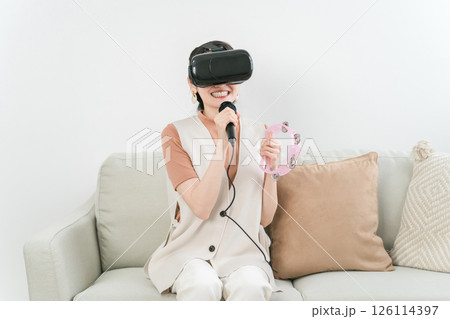 VRゴーグルをつけて家でカラオケ・メタバースを楽しむアジア人女性 VRゴーグルをつけて家でカラオケ・メタバースを楽しむアジア人女性 126114397