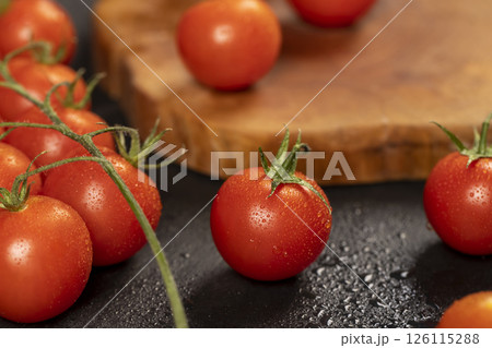 wet ripe small red tomatoes, several red round cherry tomatoes on the table , close up wet ripe small red tomatoes, several red round cherry tomatoes on the table , close up 126115288