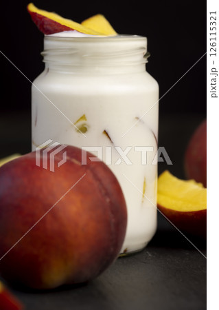 fermented milk product with peach flavor with the addition of pieces of ripe peach, closeup 126115321
