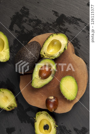 cut avocado with green flesh on a wooden board, top view cut avocado with green flesh on a wooden board, top view 126115377
