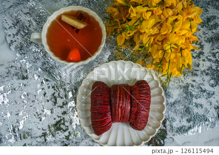 Spring tea party with yellow flowers, bow-shaped dessert and black tea on grey background 126115494
