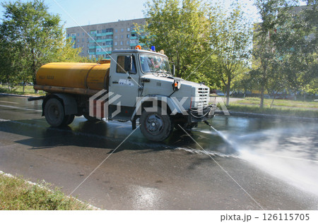 Street cleaning machine drives on the city sЫtreet. Сleaning the road with pressurized water. Using water. Watering. Cleaning concept. Front view. Powerful water jet Street cleaning machine drives on the city sЫtreet. Сleaning the road with pressurized water. Using water. Watering. Cleaning concept. Front view. Powerful water jet 126115705