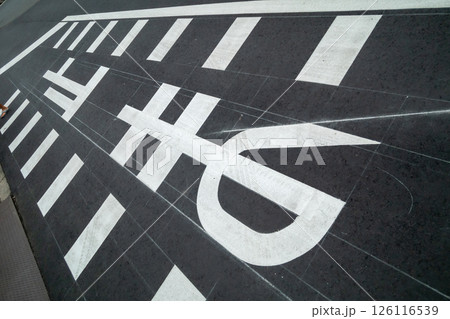 舗装したばかりのチョークの補助線跡が残っている止まれ路面標示 126116539