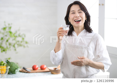 キッチンで水を飲む笑顔のミドル女性 キッチンで水を飲む笑顔のミドル女性 126116996
