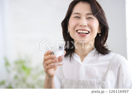 キッチンで水を飲む笑顔のミドル女性 キッチンで水を飲む笑顔のミドル女性 126116997