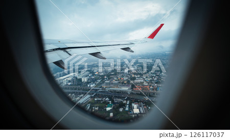 View from airplane window and airplane wing with city view on rainy day. Air travel and tourism. 126117037