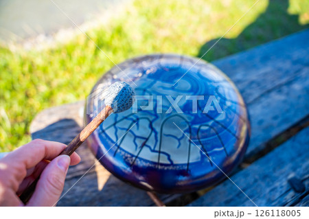 Point of view of person playing a steel tongue drum with mallets in front of mountains and river. Concept of immersive music, self-expression, and unity with natural rhythm 126118005