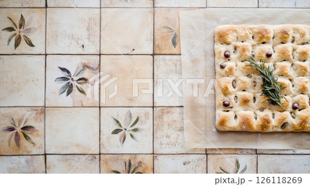 Fresh sourdough focaccia with olives and rosemary on parchment, golden crust, top view, rustic baking scene, natural daylight, simple and artisanal look 126118269