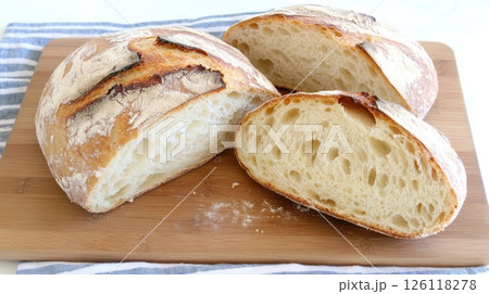 Sourdough bread sliced on a wooden board with visible porous crumb and flour dust in cozy kitchen atmosphere, perfect for artisan food and baking content. 126118278