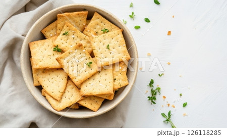 Sourdough crackers arranged in a ceramic bowl with herbs and sea salt, linen napkin, soft shadows, minimal rustic style, zero waste snack concept 126118285