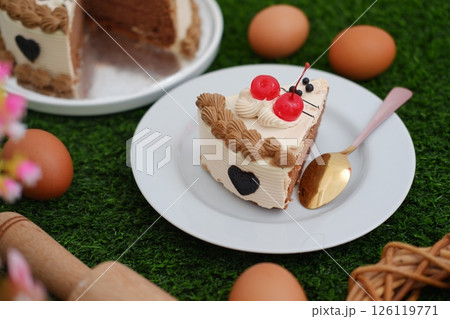 A delicious slice of chocolate cake with cherry topping on a white plate. 126119771