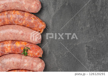 Assorted raw sausages bratwurst with spices for grill or barbeque on a stone board. Top view. Copy space 126120291