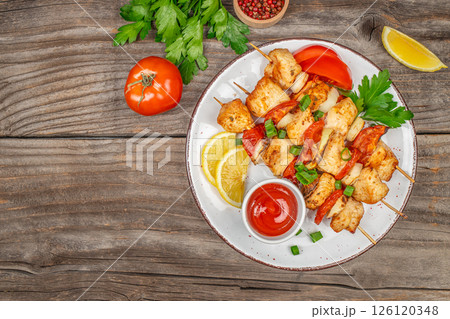 Chicken kebab skewers on a plate on a wooden background, shish kebab with tomato sauce and herbs. Top view with copy space Chicken kebab skewers on a plate on a wooden background, shish kebab with tomato sauce and herbs. Top view with copy space 126120348