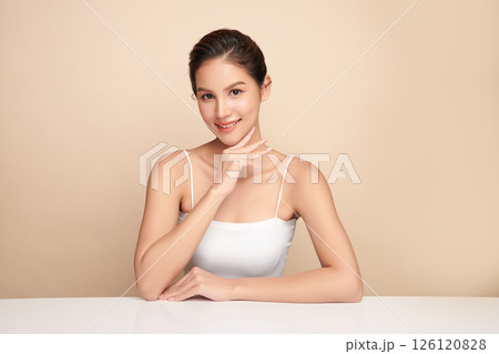 A beautiful young Asian woman with clean, fresh skin against a beige background. Skincare, facial treatment, cosmetology, beauty, and spa. An elegant portrait of an Asian woman. 126120828