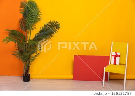 yellow chair with a gift in the interior of an orange room yellow chair with a gift in the interior of an orange room 126121787
