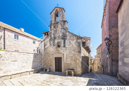 Korcula town in island of Korcula in Adriatic sea in Croatia, Europe. Ancient chapel in a European town square bathed in sunlight, featuring weathered walls, bell tower, and cobblestone paving. Korcula town in island of Korcula in Adriatic sea in Croatia, Europe. Ancient chapel in a European town square bathed in sunlight, featuring weathered walls, bell tower, and cobblestone paving. 126122365