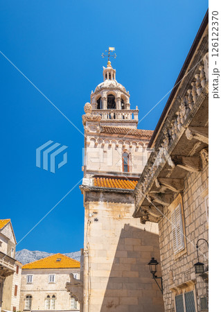 Korcula town in island of Korcula in Adriatic sea in Croatia, Europe. Architectural splendor: A weathered stone tower rises against a vibrant blue sky, showcasing detailed stonework. Korcula town in island of Korcula in Adriatic sea in Croatia, Europe. Architectural splendor: A weathered stone tower rises against a vibrant blue sky, showcasing detailed stonework. 126122370