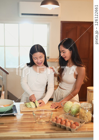 Young asian girl learning to cook with her mom in cozy home kitchen 126122661