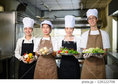 Group of culinary students proudly holding fresh vegetables, ready for their cooking class 126122706